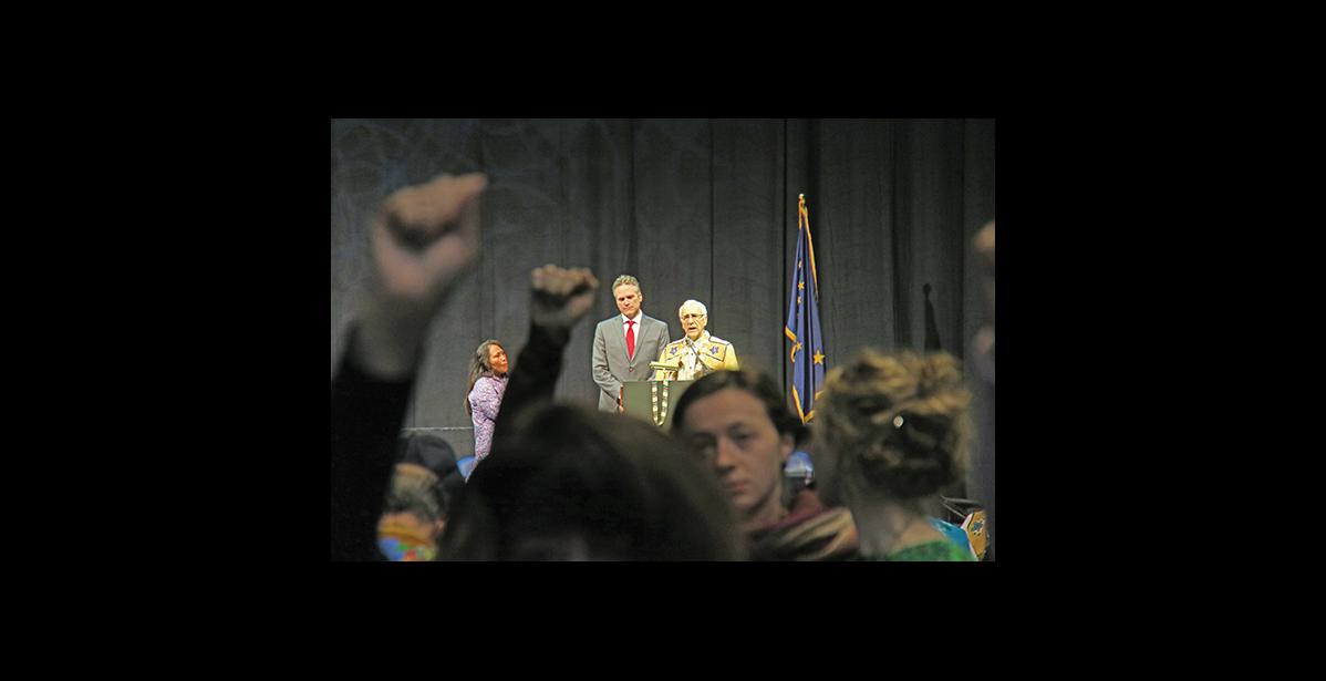 Photo by Julie St. Louis AFN Co-chairman Will Mayo interrupts Gov. Dunleavy’s speech to admonish protestors for showing disrespect to an invited speaker with their standing, fists raising, chanting and drumming.