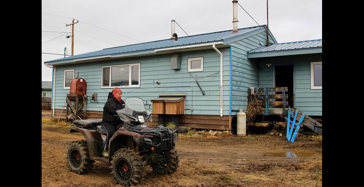 Photo by Jenni Monet Lisa Haugen, daughter of Robert "Bobby" Amarok, rides her father's four-wheeler outside his home in Golovin which faced damage from recent typhoon Merbok.
