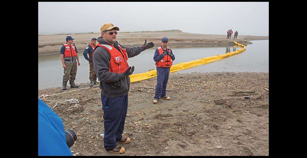 Photo by Keith Conger BOOM DEPLOYMENT— Matt Odum, left, and James Nunez, center, of the USCG led the deployment of an oil containment boom at Hastings Creek on Wednesday, June 15.