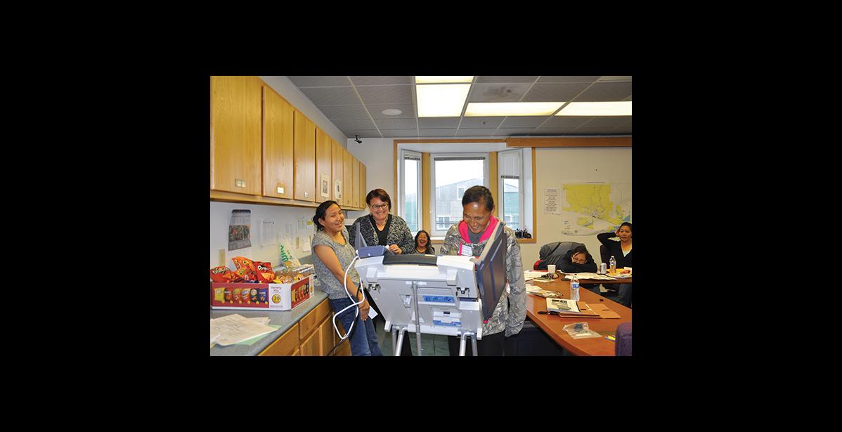 Photo by Maisie Thomas NO PEEKING—Josephine Nassuk, left, laughs with Director of Elections Josie Bahnke and Monica Giang, background, while watching her mother, Laura Nassuk, complete a practice ballot during an election worker training session on August 1 in Nome