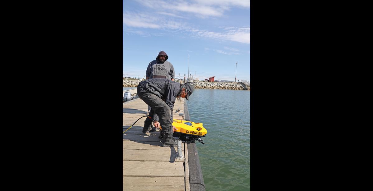 Photo by Nils Hahn DEFENDER— Wales’ Clyde Oxereok launches the Defender ROV into the Nome small boat harbor as Walter Ozenna of Diomede looks on, during a training session on Wednesday, June 12. SAR volunteers were trained for several days last week to use the newly purchased equipment by NSEDC to assist in search and rescue operations regionwide.