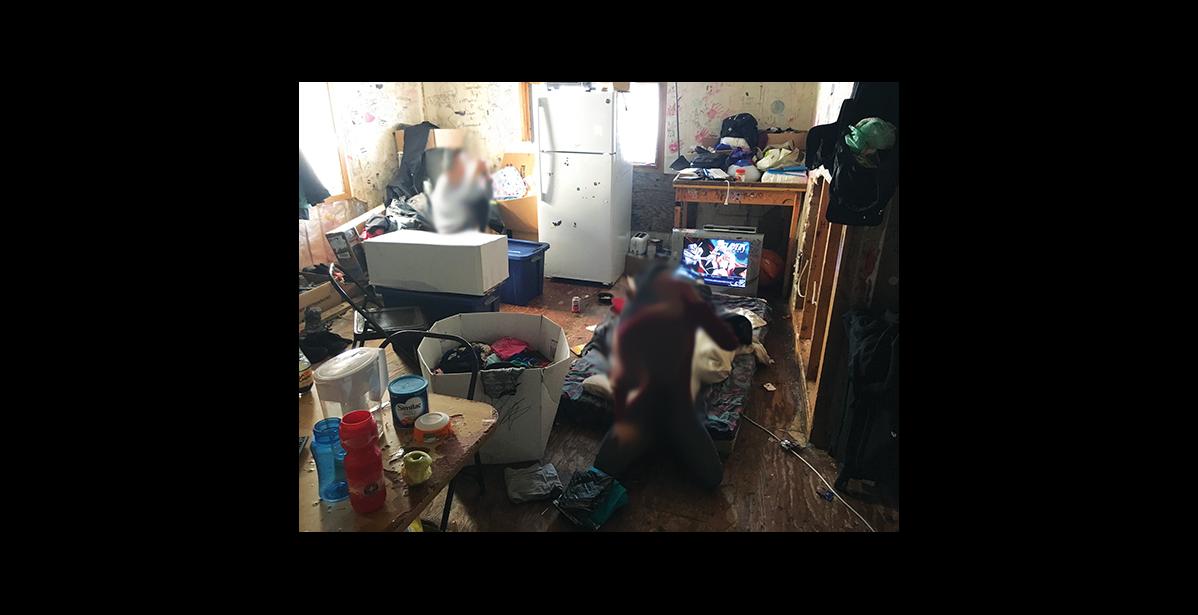 Photo courtesy Sue Steinacher NOWHERE TO GO— Two children sit on the floor of their living room in 2018. Two people sleep on the living room floor of this one-bedroom house in Savoonga, three sleep in the bedroom, and four sleep in the former kitchen.