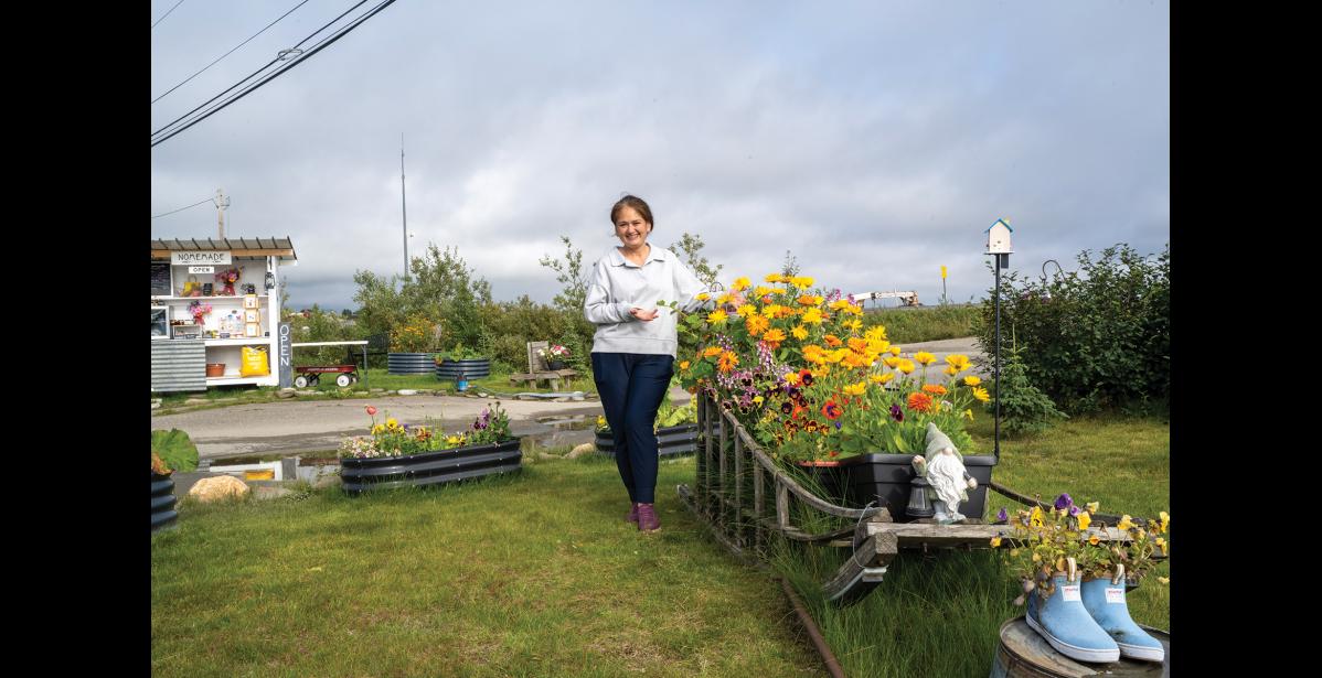 NOME GARDEN TOUR— Kim Knudsen poses with a sled covered in flowers as the Nome Garden Tour checks out her yard on Wednesday, August 19. Photo by Ariana Crockett O'Harra
