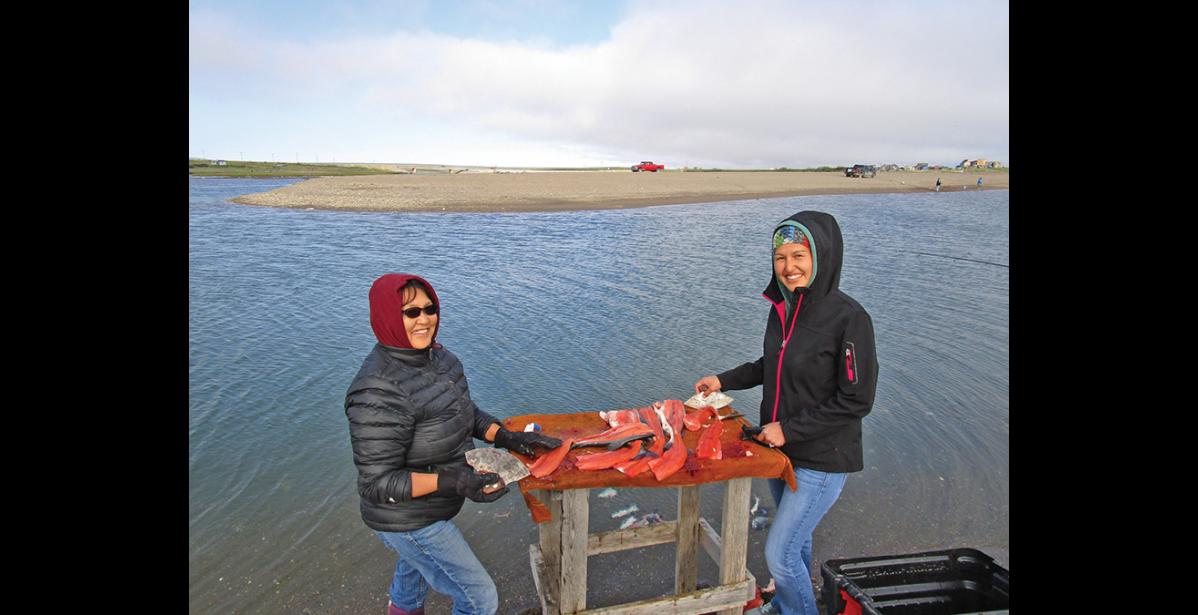 Photo by Jim Menard GONE FISHING— Marie Trigg and her niece Kellie Williams filet their catch at the mouth of the Nome River, on July 12.