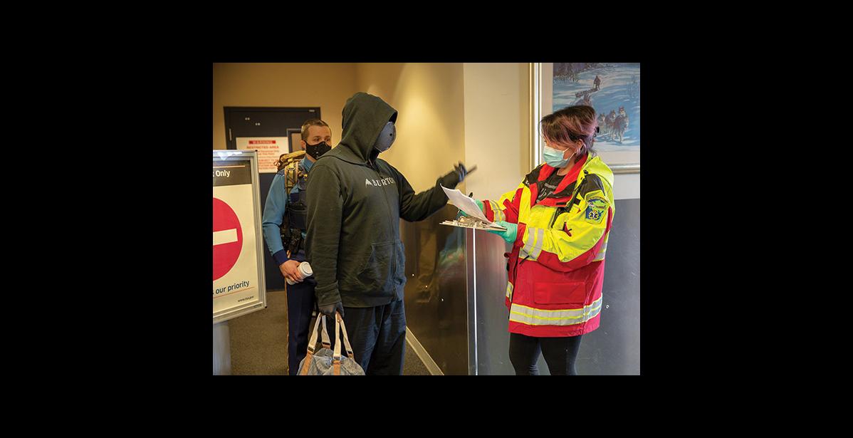 Photo by James Mason ARRIVAL IN NOME – Nome Emergency Services Technician Rose Reale checks an arrival’s travel permit in the Alaska Airlines terminal in Nome on Thursday