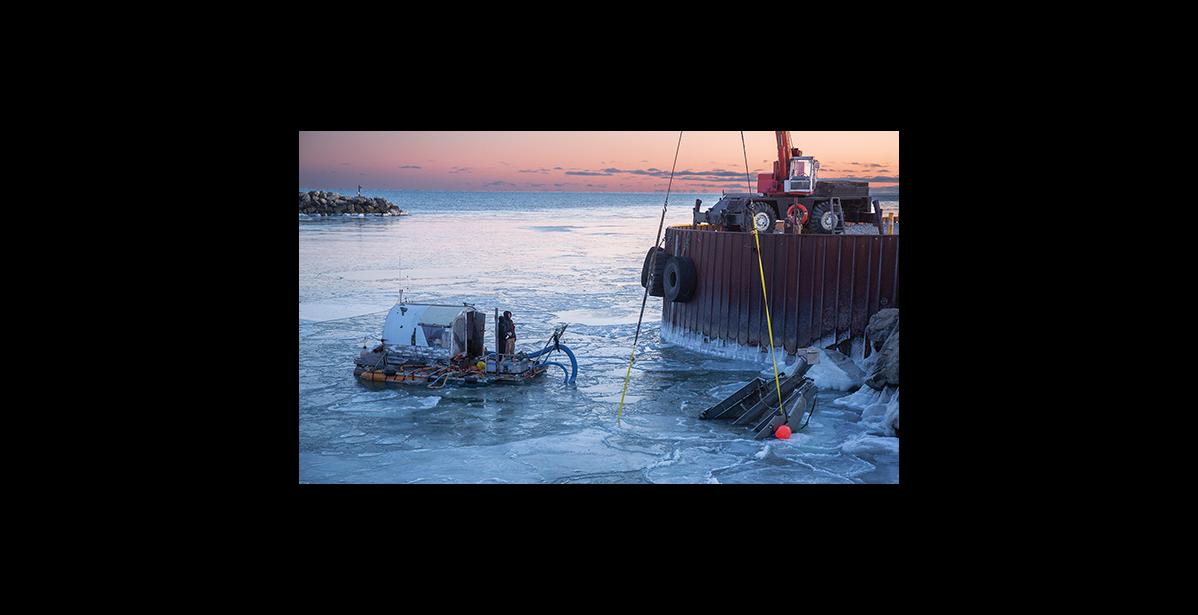 Photo by James Mason COMING UP— Jeffrey Orzechowski’s gold dredge begins to surface with the help of a crane on Monday afternoon in Nome’s outer harbor.