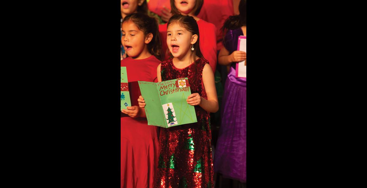 Photo by James Mason SING IT! – Second graders Hannah Harrelson and Violet Fagundes add their voices to Christmas Card during last week’s Nome Elementary Holiday Program.
