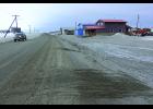Photo by Nils Hahn DUST— A car kicks up dust on Greg Kruschek Avenue in ths photo taken at the end of April. Dark snow bears witness to the prevailing problem.