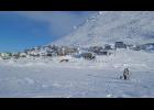 Photo by Robert Soolook LITTLE DIOMEDE— A Little Diomede man fishes through the ice in this February 2019 photo. The community of Little Diomede is shown in the background, built on the steep slopes of the island located in the middle of the Bering Strait.