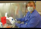Photo courtesy NSHC/Reba Lean RAPID TESTING— Alex Bahnke, a general supervisor in the NSHC Laboratory, prepares to run a COVID-19 test on one of the new Abbott ID Now machines from under the safety of a fume hood in the Nome lab.