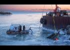 Photo by James Mason COMING UP— Jeffrey Orzechowski’s gold dredge begins to surface with the help of a crane on Monday afternoon in Nome’s outer harbor.